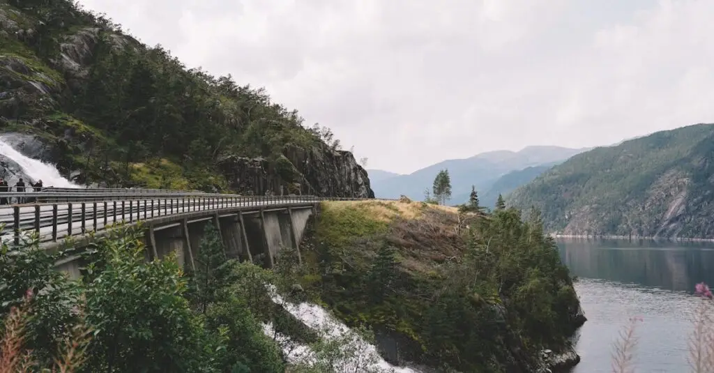 Picturesque landscape of rough mountain river running through mountainous terrain towards lake under bridge in overcast day
